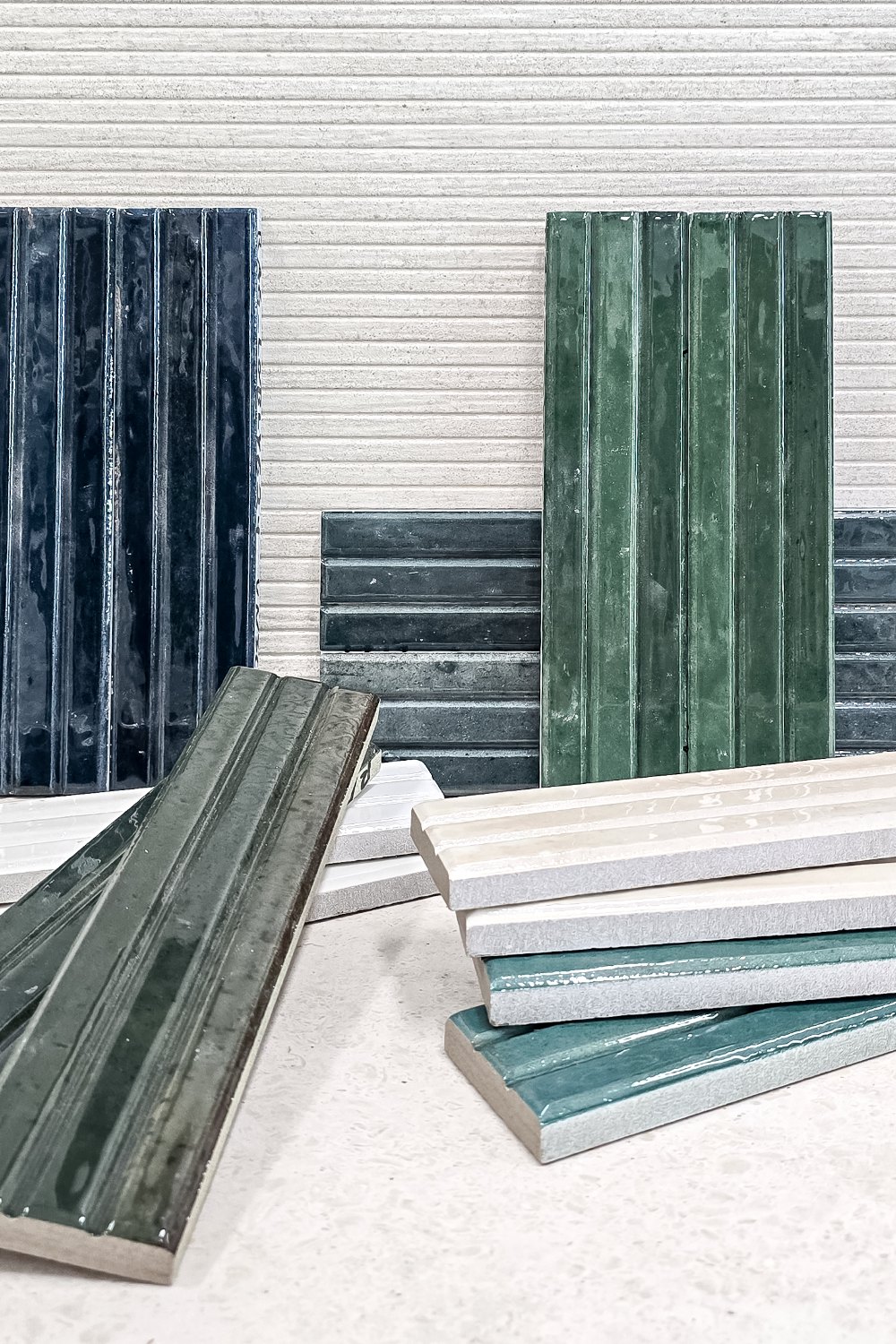 Green and teal finger tiles stacked against a white tiled wall